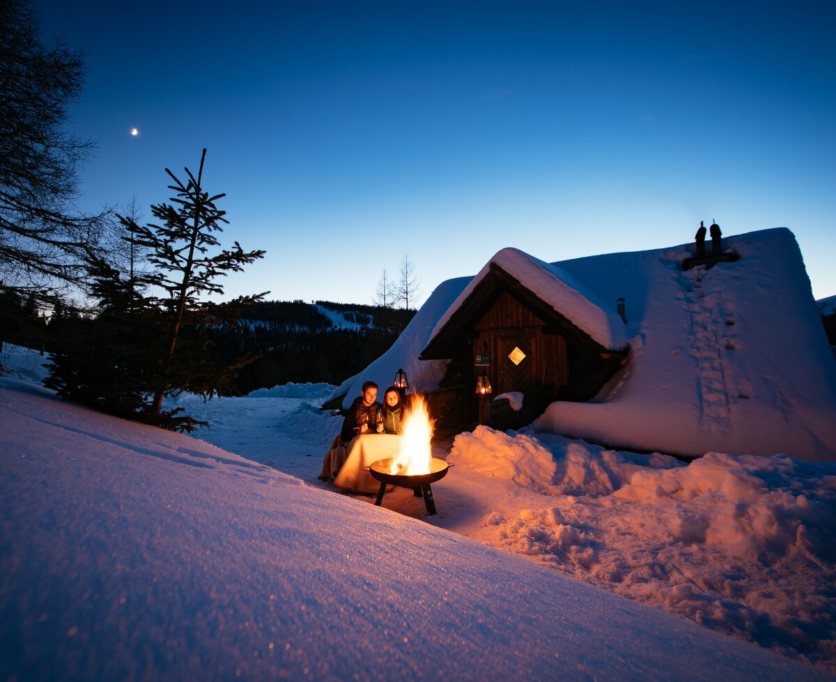 Lagerfeuerromantik auf der Almhütte | © Urlaub am Bauernhof Kärnten / Daniel Gollner Zwei Personen sitzen vor Lagerfeuer am Abend auf der Anderlehütte in Kärnten | © Urlaub am Bauernhof Kärnten / Daniel Gollner