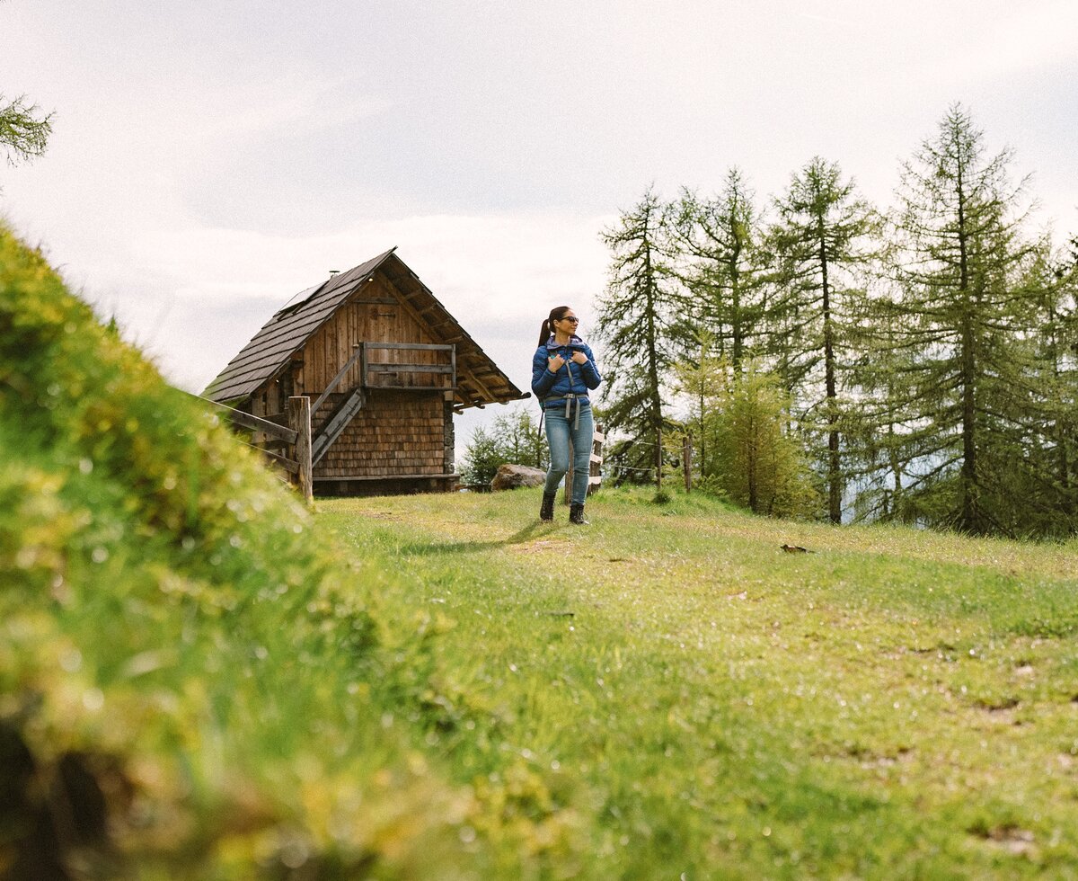 Eine Frau wandert von der Hütte weg. Im Hintergrund erkennt man die Rückseite der Almhütte. | © Urlaub am Bauernhof / Daniel Gollner