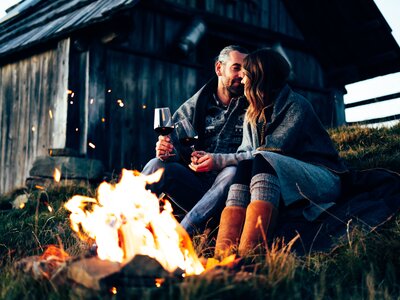 Paar genießt den Abend am Lagerfeuer | © Urlaub am Bauernhof Kärnten/ Daniel Gollner Paar sitzt vor Lagerfeuer im Gras und trinkt Wein | © Urlaub am Bauernhof Kärnten/ Daniel Gollner