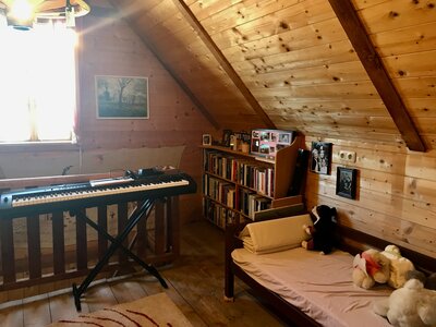 Klavier | © Urlaub am Bauernhof / Schell Gemütliches Dachzimmer mit Klavier, Bücherregal und Bett, umgeben von Holzpaneelen und Lichteinfall durch Fenster. Ruhige, heimelige Atmosphäre. | © Urlaub am Bauernhof / Schell