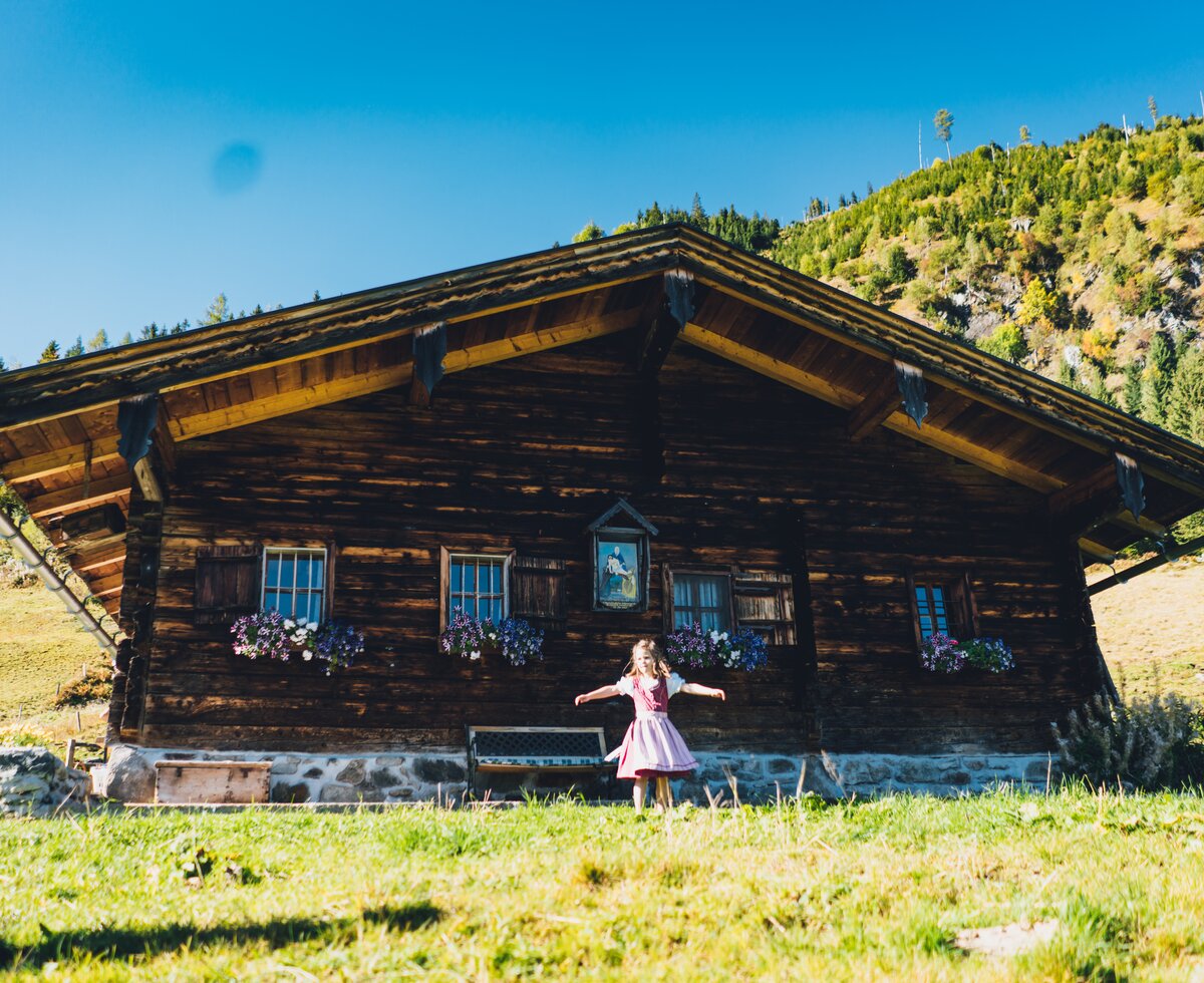 Kind im Dirndl vor der Astenhütte | © Urlaub am Bauernhof Salzburg / Daniel Gollner Kind dreht sich vor der Astenhütte im Dirndl | © Urlaub am Bauernhof Salzburg / Daniel Gollner