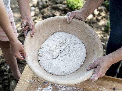 Brot im Entstehungsprozess | © Florentina Klampferer/ Urlaub am Bauernhof Kärnten Ein, zu einem Laib geformten Brotteig, wird von zwei Leuten in einer Holzschüssel gehalten | © Florentina Klampferer/ Urlaub am Bauernhof Kärnten