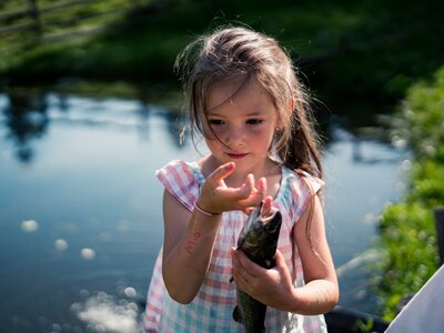 Mädchen | © Urlaub am Bauernhof Kärnten/ Daniel Gollner Mädchen hält Fisch in der Hand am Teicht | © Urlaub am Bauernhof Kärnten/ Daniel Gollner