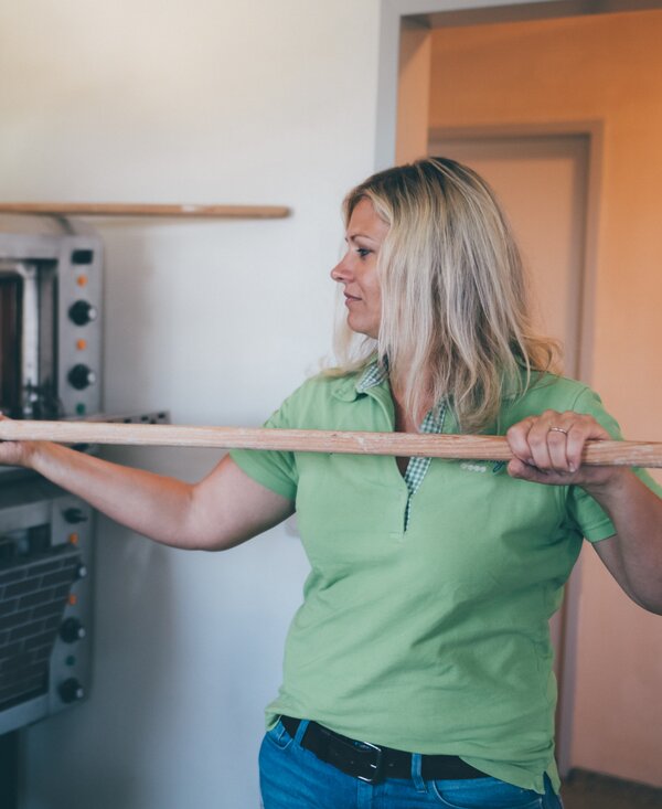 Frau schiebt das Brot in den Ofen | © Urlaub am Bauernhof Kärnten / Daniel Gollner