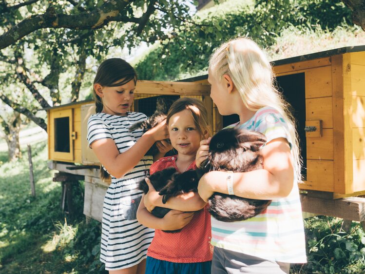 Kinder halten Hasen bei Hasenstall | © Urlaub am Bauernhof Kärnten / Daniel Gollner
