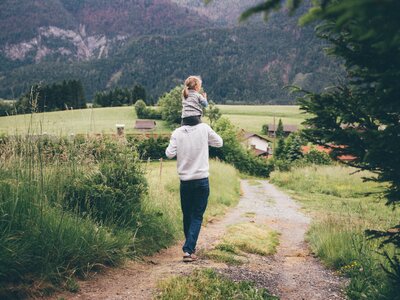 Mädchen sitzt auf den Schultern des Mannes und sie spazieren am Weg | © Urlaub am Bauernhof Kärnten / Daniel Gollner