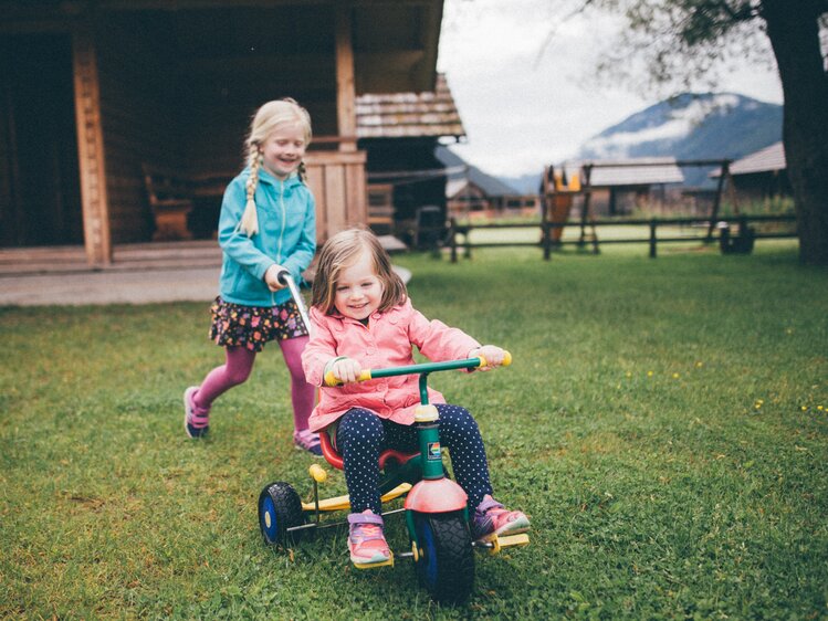 Kinder mit dem Dreirad auf der Wiese | © Urlaub am Bauernhof Kärnten / Daniel Gollner