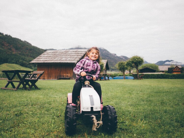 Mädchen mit Spielzeugtraktor auf der Wiese | © Urlaub am Bauernhof Kärnten / Daniel Gollner
