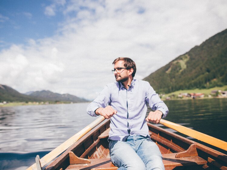 Mann sitzt im Boot am Wasser | © Urlaub am Bauernhof Kärnten / Daniel Gollner