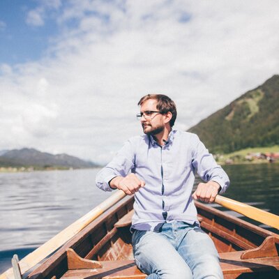 Mann sitzt im Boot am Wasser | © Urlaub am Bauernhof Kärnten / Daniel Gollner