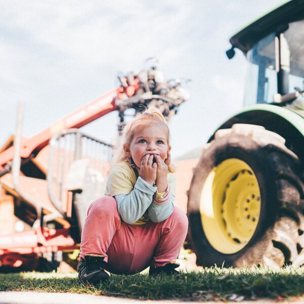 Mädchen hockt vor dem Traktor | © Urlaub am Bauernhof Kärnten / Daniel Gollner