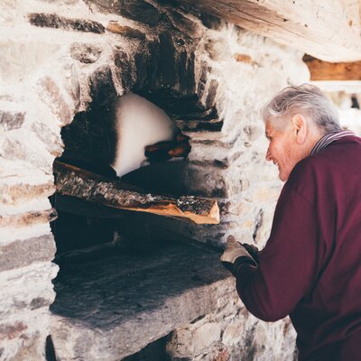 Bäuerin gibt Holz in den Ofen | © Urlaub am Bauernhof Kärnten / Daniel Gollner
