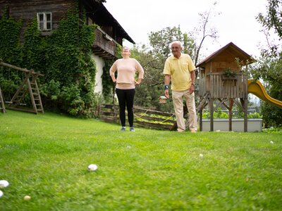Alexanders Frau und Opa Erich beim Alm-Boccia-Spielen im Garten | © Urlaub am Bauernhof Kärnten / Daniel Gollner Mann und Frau spielen im Garten mit Kugeln | © Urlaub am Bauernhof Kärnten / Daniel Gollner