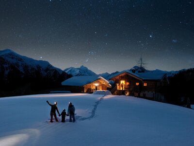Die Nacht der Sterne im Winter in den Hohen Tauern | © Klaus Dapra Familie blickt auf Sternenhimmel mit Hütte im Hintergrund | © Klaus Dapra