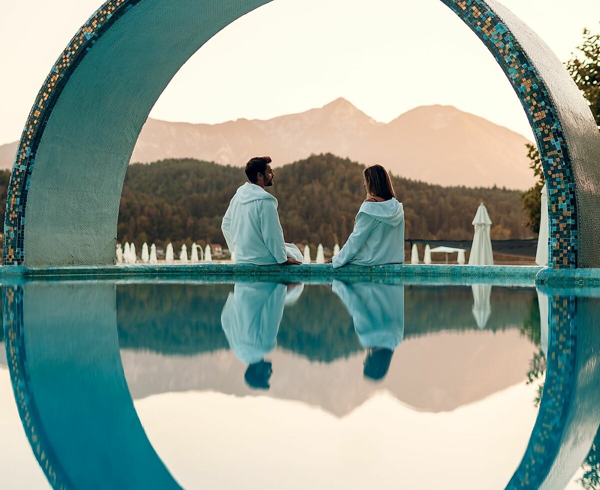 Seenwellness in Südkärnten | © Tourismusregion Klopeiner See - Südkärnten GmbH / Martin Hofmann Paar sitzt am Rand des Pools im Hintergrund See und Landschaft | © Tourismusregion Klopeiner See - Südkärnten GmbH / Martin Hofmann