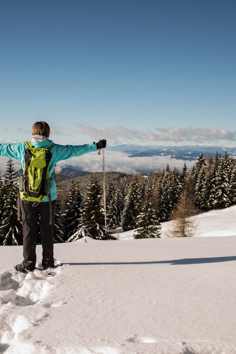 Schneeschuhwanderin steht im Tiefschnee und hebt die Arme | © Tourismusregion Mittelkärnten 
