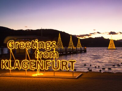 beleuchtet Grüße aus Klagenfurt Tafel vor dem Wörthersee im Winter zum Sonnenuntergang | © Pixelpoint Multimedia GmbH 