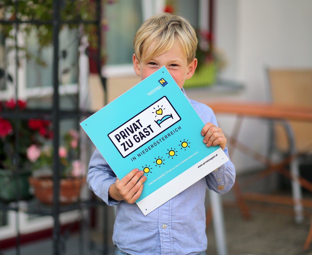 Bub hält Privat zu Gast Tafel in der Hand | © Privat zu Gast in Niederösterreich / weinfranz.at