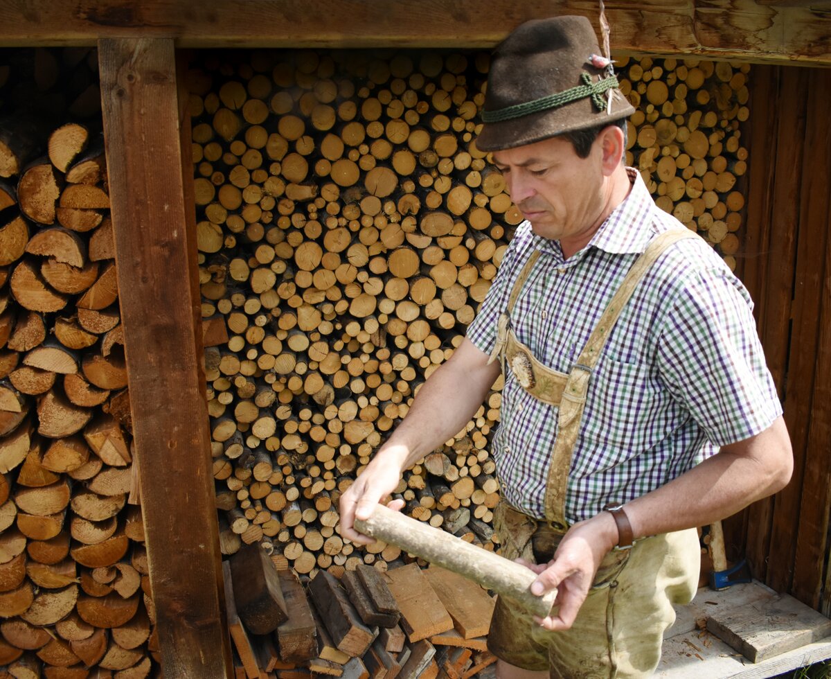 Bauer zeigt ein Stück Holz her | © Urlaub am Bauernhof Oberösterreich / Harald Puchegger