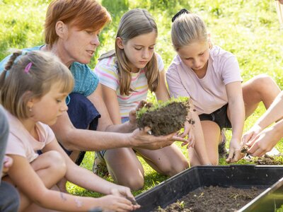 Schauen wir uns näher an, wer im Boden lebt | © Urlaub am Bauernhof Oberösterreich / puremotions photography Bäuerin zeigt Kindern Bodelebewesen | © Urlaub am Bauernhof Oberösterreich / puremotions photography