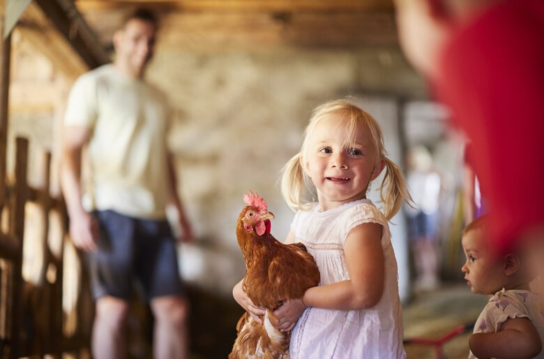 Mädchen hält ein Huhn auf dem Arm | © Urlaub am Bauernhof Oberösterreich / Alexander Kaiser