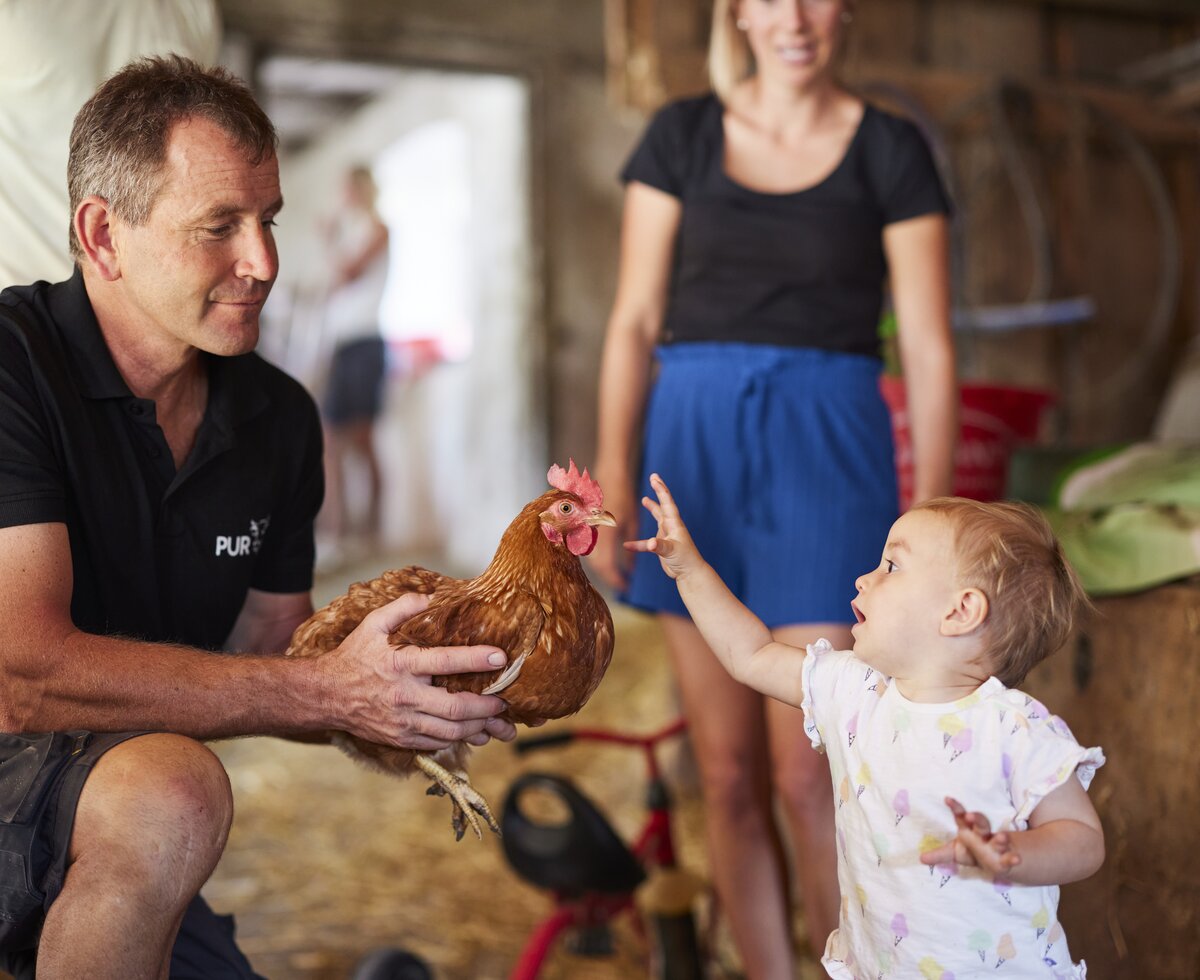 Bauer zeigt Baby ein Huhn | © Urlaub am Bauernhof Oberösterreich / Alexander Kaiser