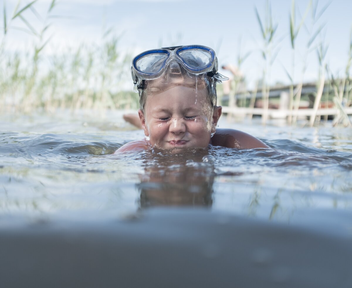 Sommerurlaub am See | © Urlaub am Bauernhof Oberösterreich / Robert Maybach Bub mit Taucherbrille badet im See und prustet ins Wasser | © Urlaub am Bauernhof Oberösterreich / Robert Maybach