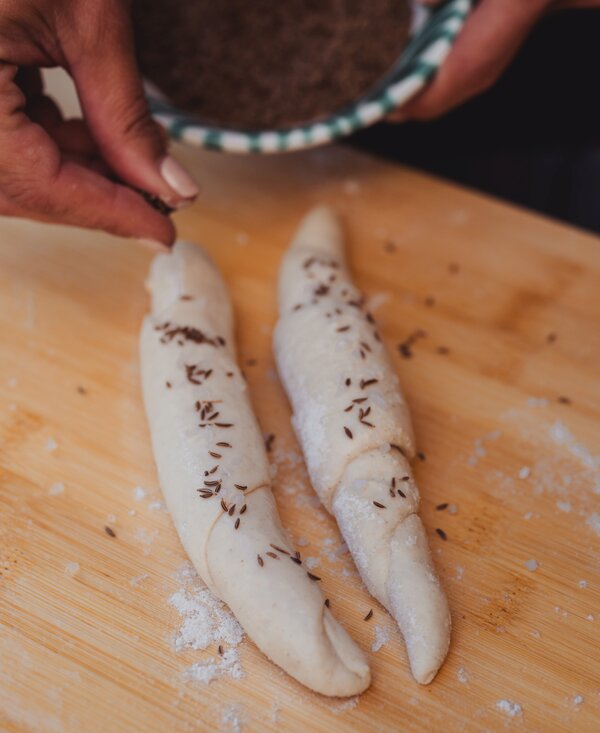Salzstangerl mit Salz und Kümmel bestreuen | © Footprints Fotografie // cookingCatrin