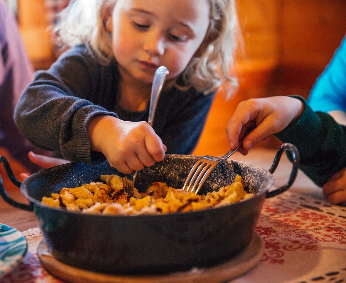 Kaiserschmarren für die ganze Familie | © Urlaub am Bauernhof Oberösterreich / Pascal Baronit Mädchen isst aus einer Pfanne mit Kaiserschmarren | © Urlaub am Bauernhof Oberösterreich / Pascal Baronit