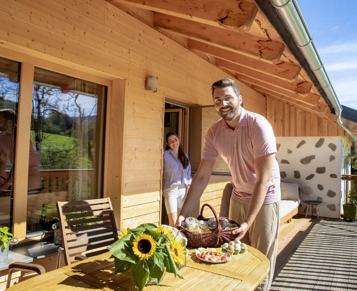 Frühstück ist fertig - mit vielen Produkten direkt vom Hof | © Urlaub am Bauernhof Oberösterreich / puremotions photography Mann richtet Frühstück auf der Terrasse für seine Partnerin an | © Urlaub am Bauernhof Oberösterreich / puremotions photography