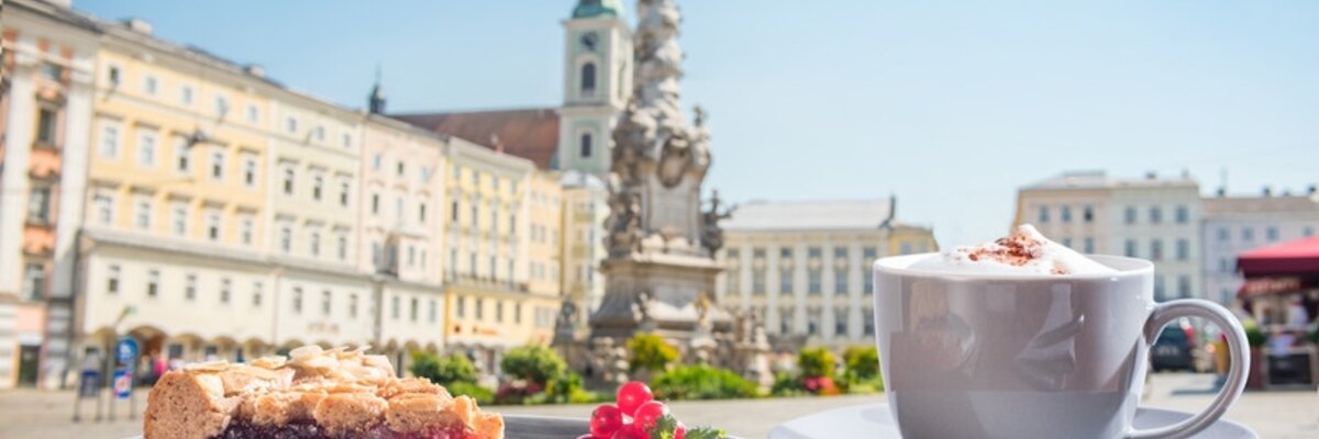 Ein Stück Linzer Torte und ein Cappuccino in einem Gastgarten mit Blick auf den Linzer Hauptplatz | © Linz Tourismus / ms Fotogroup