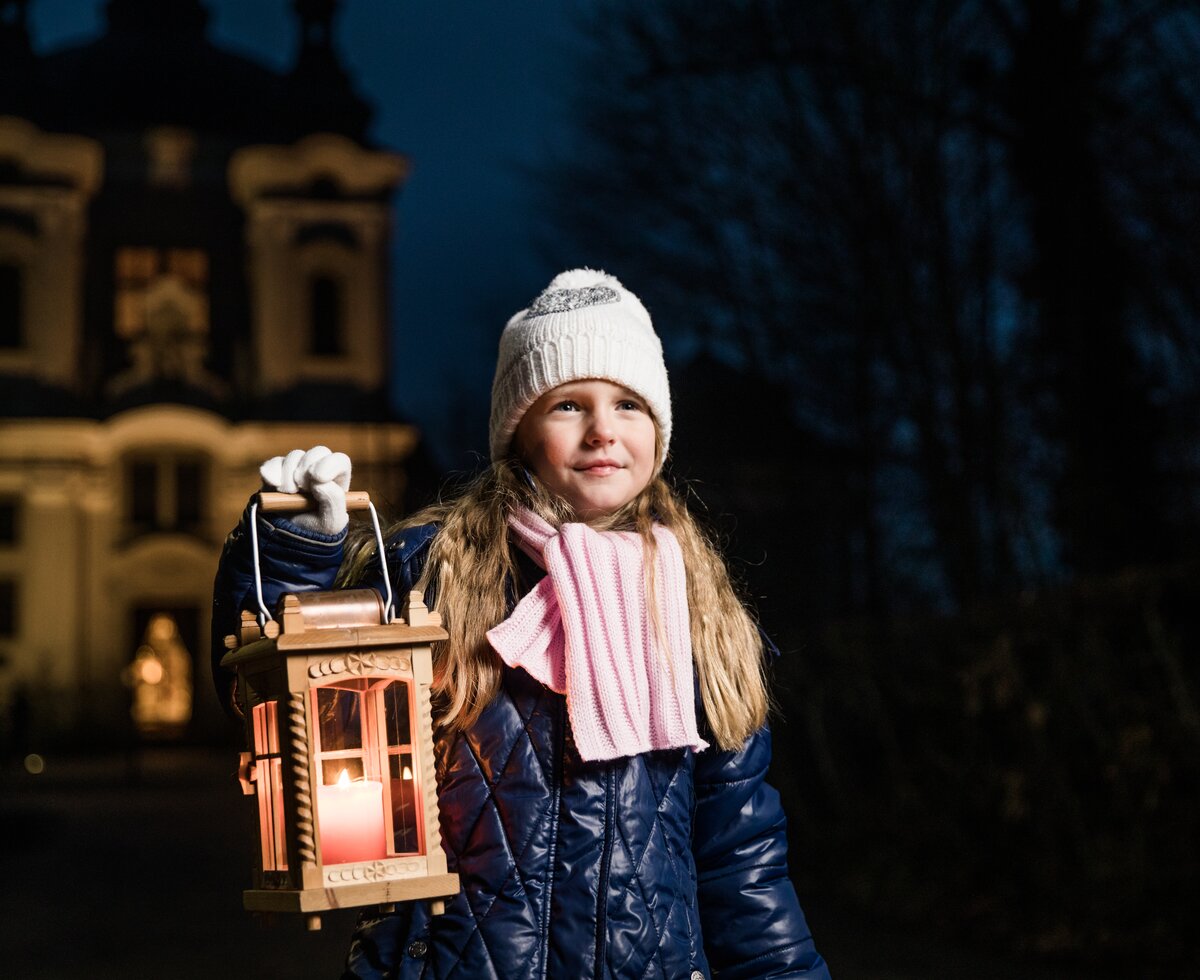Mädchen steht abends im Advent mit einer Laterne vor der Kirche | © Oberösterreich Tourismus GmbH / Robert Maybach