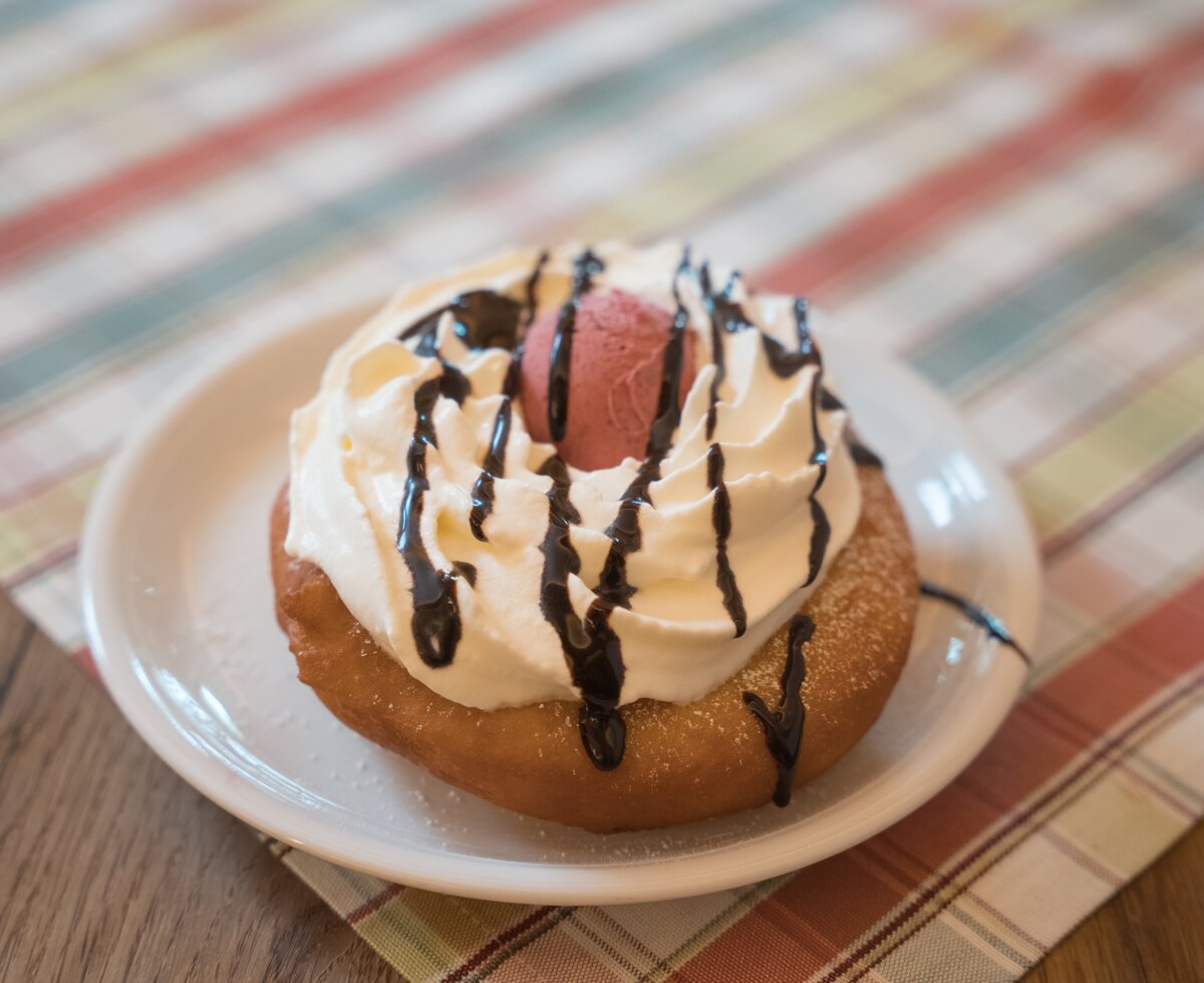 Fertiger Bauernkrapfen mit Mosteis | © Urlaub am Bauernhof / Daniel Gollner Leckerer Donut mit Sahne und Schokoladentopping auf einem gestreiften Untergrund. | © Urlaub am Bauernhof / Daniel Gollner