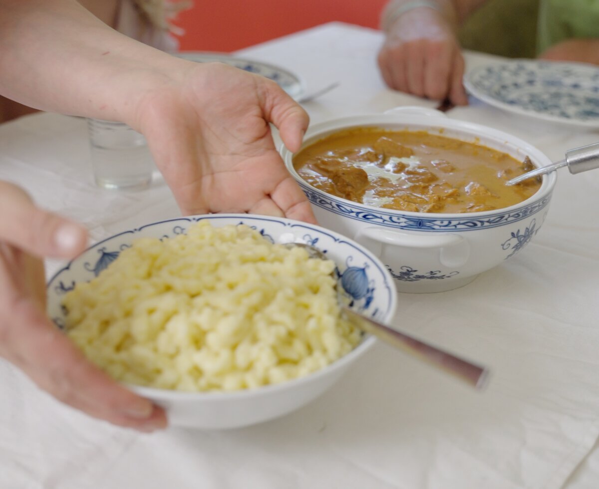 Eine Person bereitet ein Gericht mit cremiger Sauce und Reis in traditionellen Schüsseln zu, bereit für einen Genuss. | © Urlaub am Bauernhof / Daniel Gollner