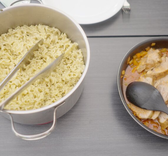 In einer Schüssel angerichtete, goldene Nudeln mit Essstäbchen, daneben eine Schüssel mit dunkler Sauce und einem Löffel. | © Urlaub am Bauernhof / Daniel Gollner