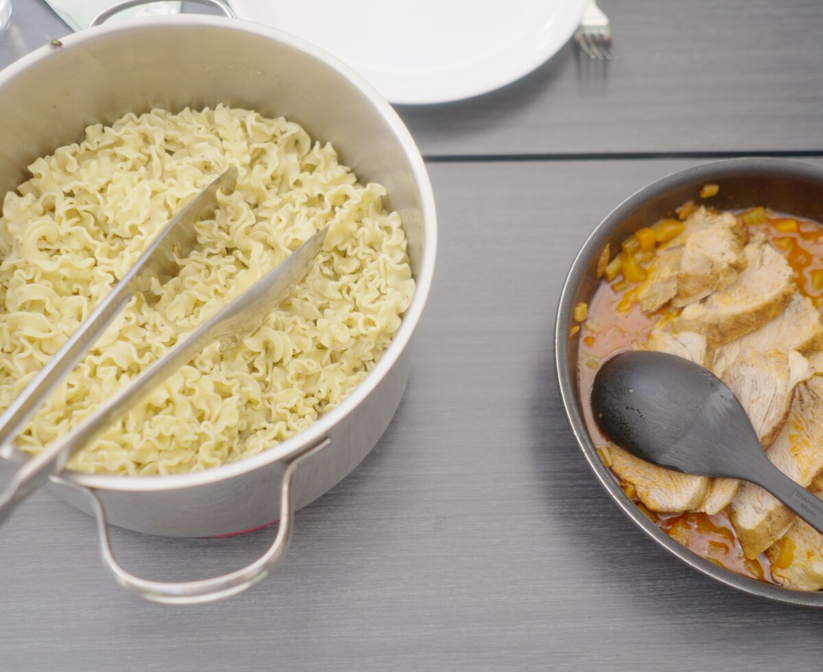 In einer Schüssel angerichtete, goldene Nudeln mit Essstäbchen, daneben eine Schüssel mit dunkler Sauce und einem Löffel. | © Urlaub am Bauernhof / Daniel Gollner