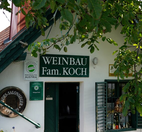 Grünangestrichenes Fachwerkhaus mit Eingang und Schildern, umgeben von grünen Blättern und Efeu. Ein traditionelles Panorama mit einer Atmosphäre von Gemütlichkeit und Ländlichkeit. | © Urlaub am Bauernhof / Daniel Gollner