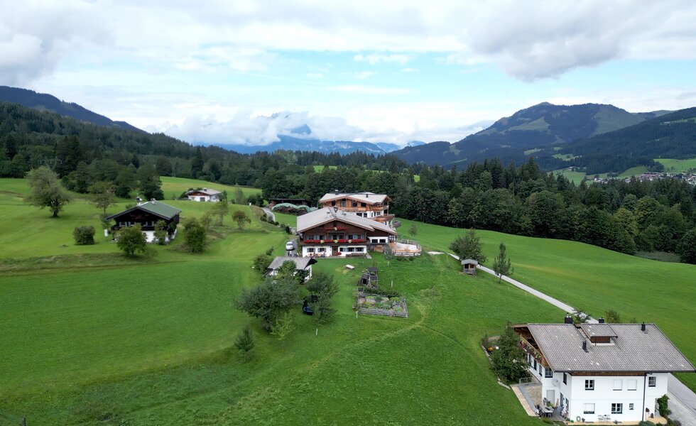 Idyllische Berglandschaft mit Häusern, Wiesen und Wäldern. Charmantes alpines Ambiente mit traditioneller Architektur inmitten einer grünen, hügeligen Umgebung. | © Urlaub am Bauernhof / Daniel Gollner