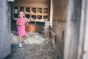 Young child in pink dress carrying a wicker basket through an old, rustic interior. | © Urlaub am Bauernhof / Daniel Gollner