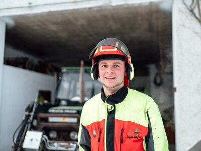 Bauer mit Schutzkleidung | © Urlaub am Bauernhof / Daniel Gollner Bauer mit Schutzkleidung neben dem Traktor | © Urlaub am Bauernhof / Daniel Gollner