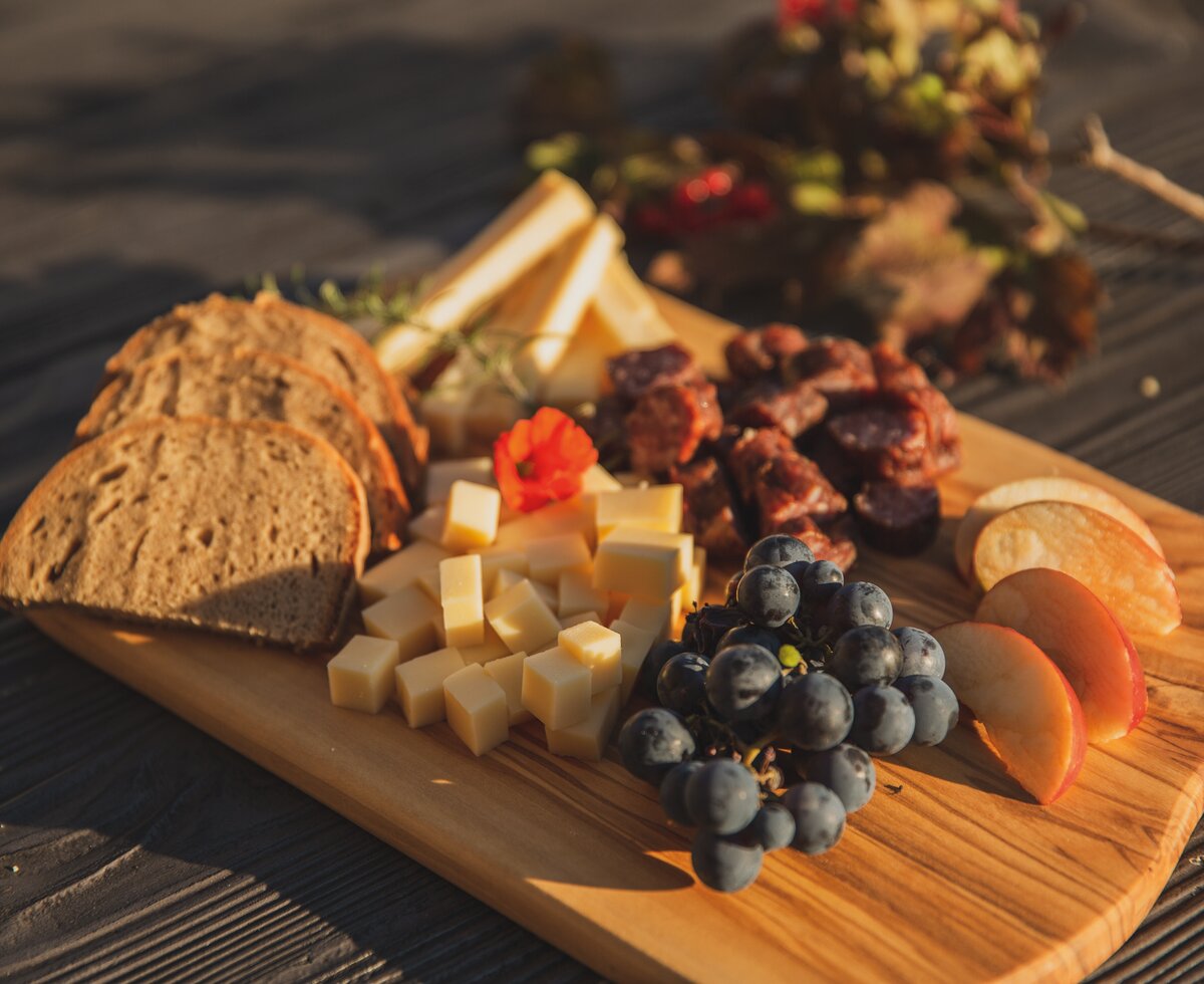 Brettljause | © Urlaub am Bauernhof in Österreich / Pascal Baronit Brettljause mit Brot, Käse, Weintrauben und Apfelscheiben auf dem Holztisch | © Urlaub am Bauernhof in Österreich / Pascal Baronit