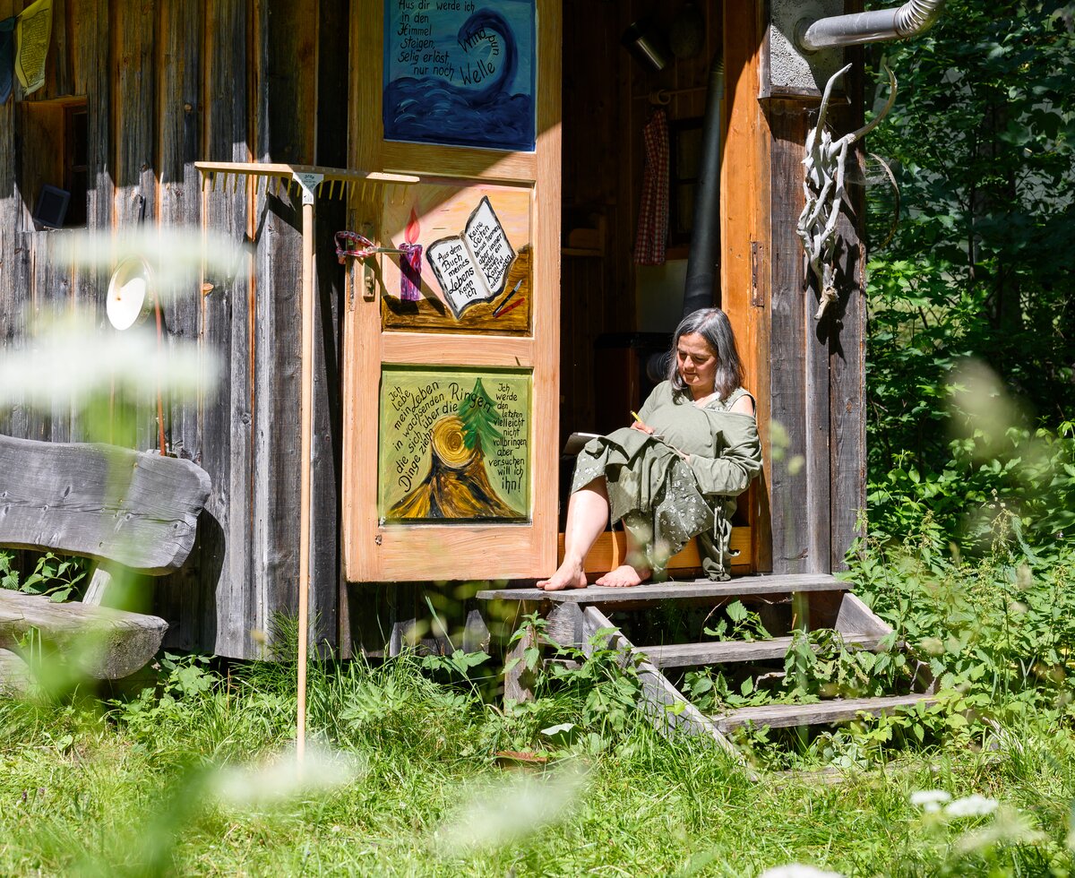 Frau sitzt auf Stufen vor einer Hütte | © Urlaub am Bauernhof Frau sitzt auf Stufen vor einer Hütte | © Urlaub am Bauernhof