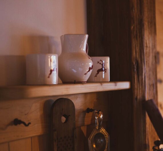 Holzregale mit Keramikvasen, Dekorationselementen und Werkzeugen an der Wand in einem gemütlichen, rustikalen Ambiente. | © Urlaub am Bauernhof / Pascal Baronit