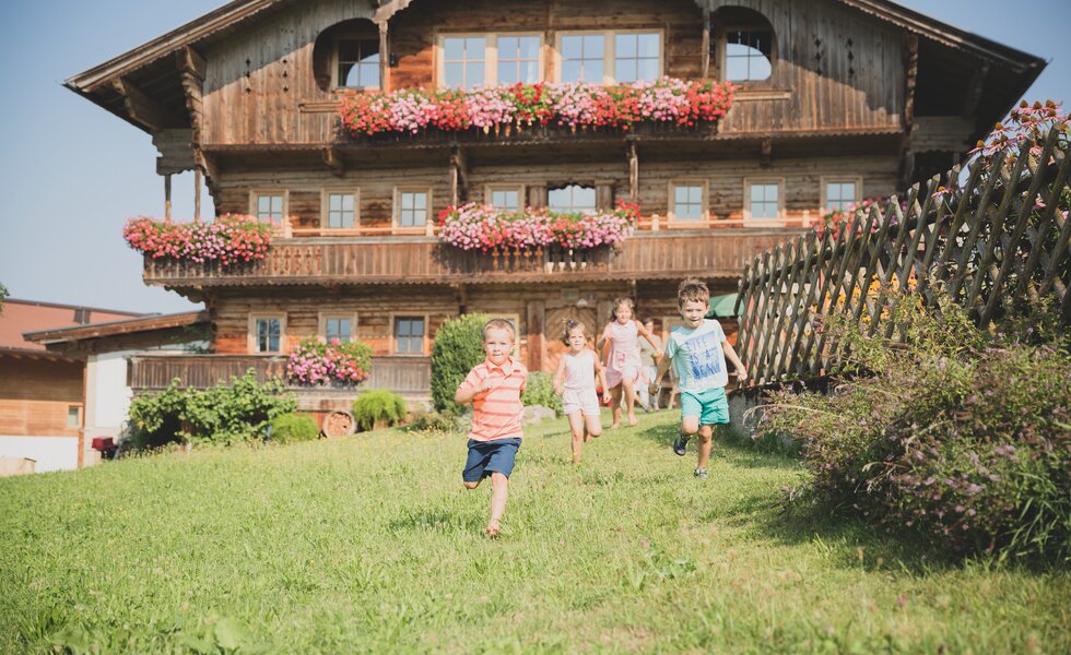 4 Kinder laufen vor Bauernhof | © Urlaub am Bauernhof Österreich / Pascal Baronit