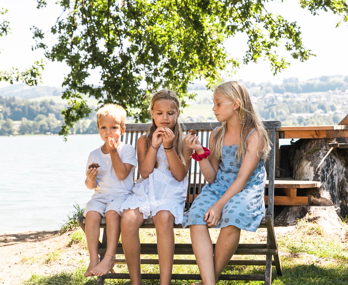 Kinder sitzen auf der Bank | © Urlaub am Bauernhof / Punkt und Komma drei kinder sitzen auf einer Bank und essen | © Urlaub am Bauernhof / Punkt und Komma