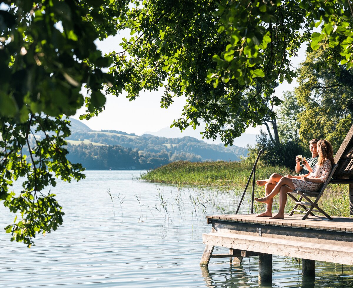 Bank am See | © Urlaub am Bauernhof / Punkt und Komma ein Paar sitzt auf eienr bank am Steg neben dem See | © Urlaub am Bauernhof / Punkt und Komma