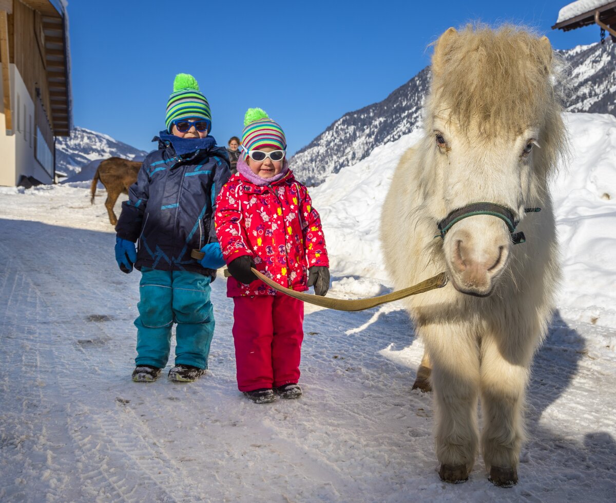 zwei Kinder mit Pferd im Schnee | © Urlaub am Bauernhof / Bernd Suppan zwei Kinder stehen mit weißen Pferd in Schneelandschaft | © Urlaub am Bauernhof / Bernd Suppan