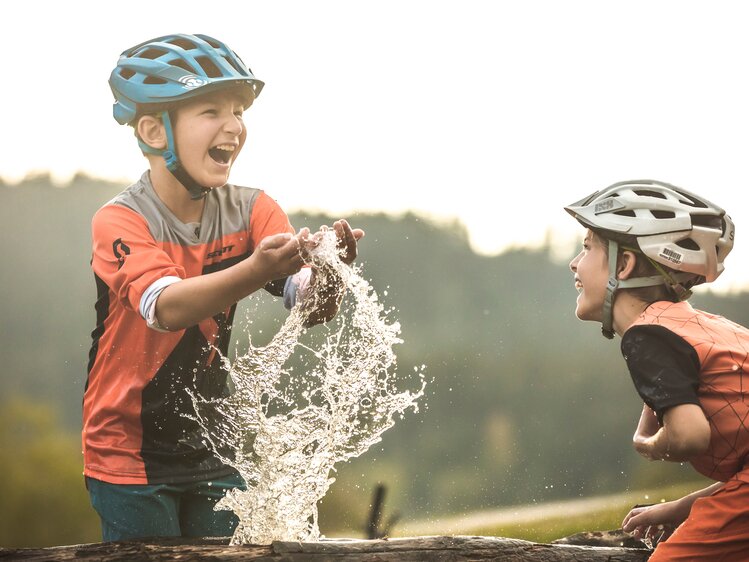 Kinder mit Fahradhelm beim Spielen am Wasserbrunnen. | © SalzburgerLand Tourismus/Klemens König