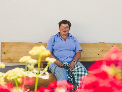 Gastgeberin sitzt auf dem Hausbankerl | © Urlaub am Bauernhof im SalzburgerLand / Matthias Gruber Gastgeberin Karin Pöllmann vom Stallerbauer in Ried am Wolfgangsee sitzt auf dem Hausbankerl. | © Urlaub am Bauernhof im SalzburgerLand / Matthias Gruber