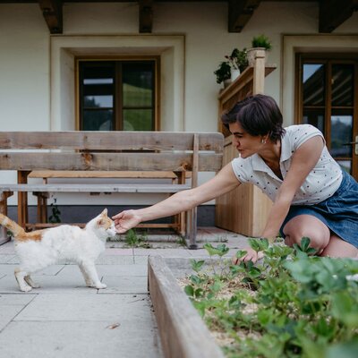 Baeuerin mit Katze im Garten | © Urlaub am Bauernhof / Nadia Jabil